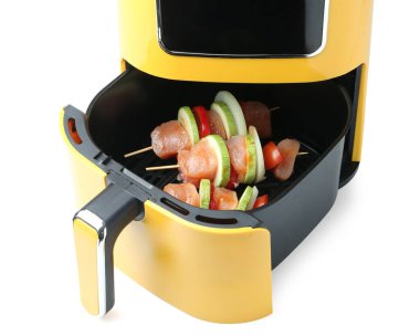 Kızartma makinesinde çiğ tavuk ve sebzeli şişler beyaza izole edilmiş.