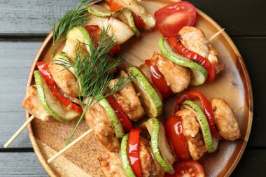 Ahşap masada ızgara tavuk ve sebzeli şişler.