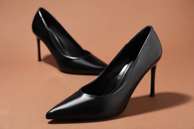 Kahverengi arka planda şık topuklu ayakkabılar, yakın plan.