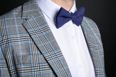 Siyah arka planda şık papyonlu takım elbiseli adam, yakın plan.