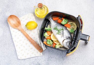 Çiğ balık, limon ve sebzeler kızartma makinesinde açık gri masada, düz yatıyordu.