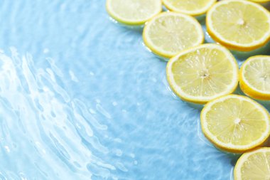 Açık mavi arka planda limon dilimleri, yakın plan. Metin için boşluk