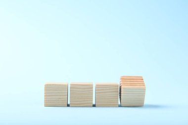Blank wooden cubes on light blue background, space for text