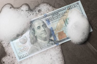 Para aklama. Siyah masa üzerinde dolar banknot ve köpük, üst görünüm