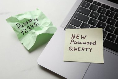 Şifre değiştiriliyor. Yeni ve eski şifreli kâğıt notlar ve beyaz masada dizüstü bilgisayar