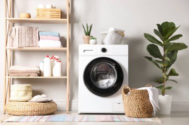 Çamaşır odasında çamaşır, deterjan ve çiçekli çamaşır makinesi. İç tasarım