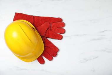 Koruyucu şapka ve eldivenler beyaz mermer masada, düz yerde. Metin için boşluk