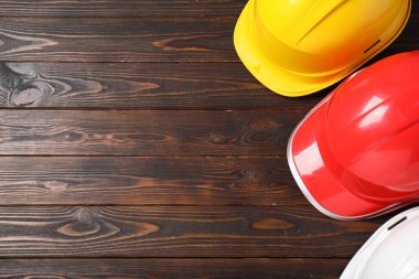 Ahşap masadaki sert şapkalar, düz yatış, yazı için yer. Güvenlik ekipmanları