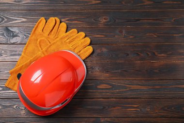 Ahşap masada sert şapka ve koruyucu eldivenler, yazı için yeri olan üst manzara. Güvenlik ekipmanları