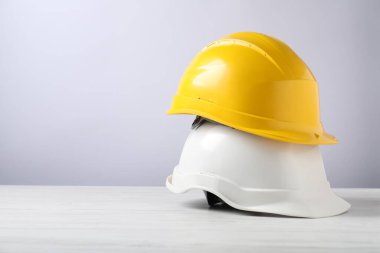 Beyaz ahşap masada sert şapkalar, yazı için yer. Güvenlik ekipmanları