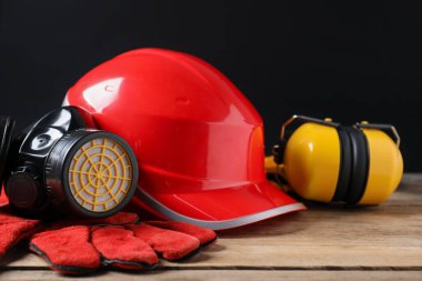 Ahşap masada farklı güvenlik ekipmanları, yakın plan.