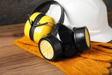 Ahşap masada farklı güvenlik ekipmanları, yakın plan.