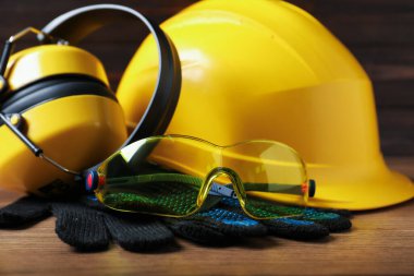 Ahşap masada farklı güvenlik ekipmanları, yakın plan.