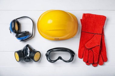 Beyaz ahşap masada farklı güvenlik ekipmanları var.