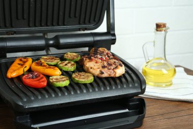 Mutfaktaki ahşap masada biftek ve sebzeli ızgara, yakın plan.