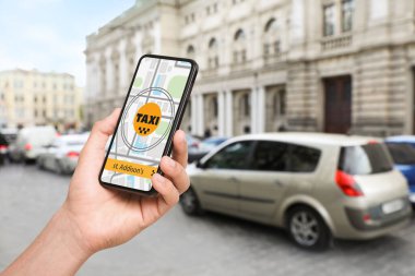 Şehir caddesinde taksi çağırmak için cep telefonu uygulaması kullanan bir adam.