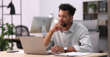 Masada dizüstü bilgisayarı olan bir adam var.
