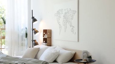 Büyük rahat bir yatak, yan masa ve lamba yatak odasındaki beyaz duvarın yanında, kamera aşağı iniyor.