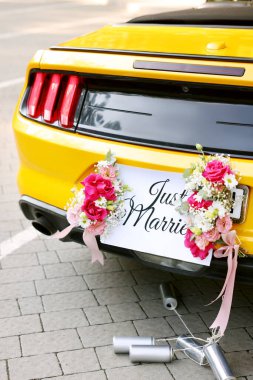 Düğün arabası. Cabriolet sadece evlilik kartıyla dekore edilmiş, güzel çiçekler ve teneke kutular, yakın plan.
