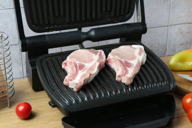 Tahta masada çiğ etle elektrikli ızgara, yakın plan.