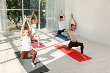 Bir grup ergen ve eğitmen içeride minderlerde yoga yapıyor.