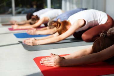 İçerideki minderlerde yoga yapan bir grup genç.