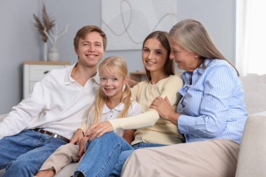 Oğlunun ailesiyle birlikte evdeki kanepede oturan yaşlı kadın.