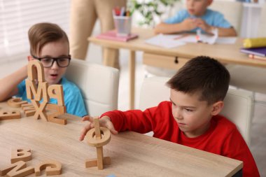 İlkokulda ahşap masalarda ders alan küçük çocuklar, yakın çekim.