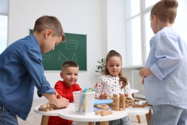 İlkokulda ders sırasında beyaz masada oturan sevimli çocuklar.