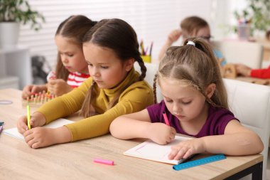 İlkokulda ahşap masada ders alan çocuklar, yakın çekim.