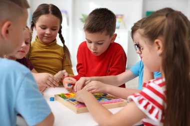 İlkokulda ders sırasında beyaz masada oturan sevimli çocuklar.