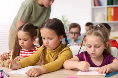 İlkokulda ahşap masada öğretmenden ders alan çocuklar, yakın çekim.
