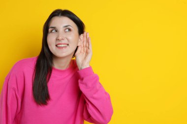 Gülümseyen kadın sarı arka planda el ele hareketler gösteriyor. Metin için boşluk