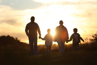 Aile gün batımında el ele tutuşuyor.