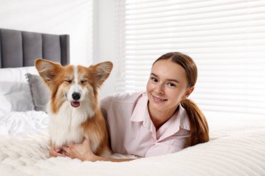 Evcil hayvan dostu otel. Güzel Galli Corgi köpeğiyle yatakta gülümseyen kadın.