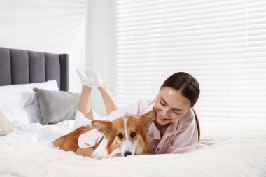 Evcil hayvan dostu otel. Güzel Galli Corgi köpeğiyle yatakta gülümseyen kadın.
