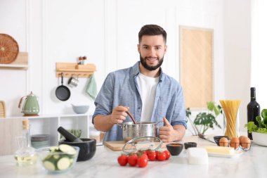 Mutfaktaki masada yemek pişiren gülümseyen adam.