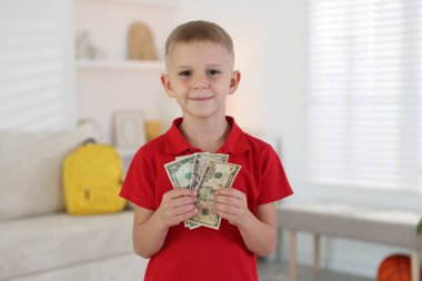 Evde cep harçlığı tutan küçük çocuk.