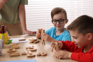 İlkokulda ahşap masada öğretmenden ders alan küçük çocuklar, yakın çekim.