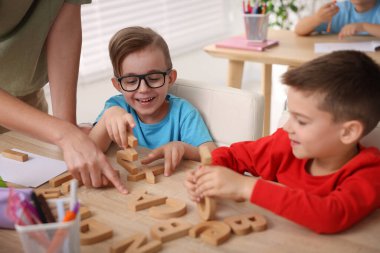 İlkokulda ahşap masada öğretmenden ders alan küçük çocuklar, yakın çekim.