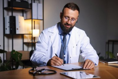 Doktor, gece vardiyası sırasında klinikteki masada notlar yazıyor.