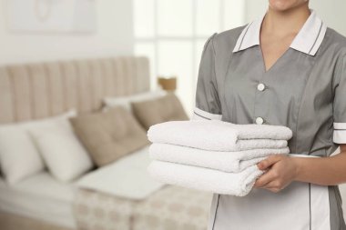Otel odasında temiz havluları olan oda hizmetçisi.