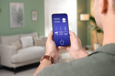 Adam cep telefonunda akıllı ev uygulaması kullanıyor.