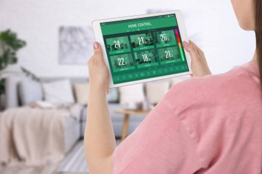 Odadaki tablet bilgisayarda akıllı ev uygulaması kullanan kadın, kapat