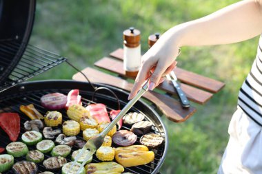 Vejetaryen barbeküsü. Dışarıdaki ızgarada sebze pişiren kadın, yakın plan.
