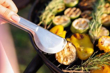 Vejetaryen barbeküsü. Dışarıdaki ızgarada sebze pişiren kadın, yakın plan.