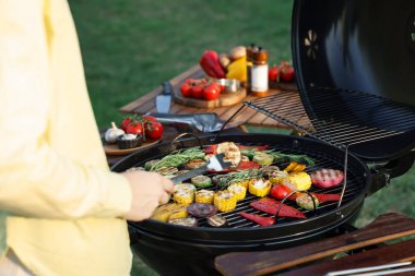 Vejetaryen barbeküsü. Dışarıdaki ızgarada sebze pişiren kadın, yakın plan.