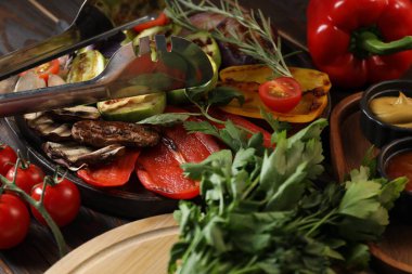 Vejetaryen barbeküsü. Ahşap masada servis edilen lezzetli ızgara sebzeler, yakın plan.