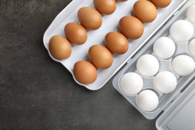 Gri masadaki plastik kaplarda çiğ tavuk yumurtası. Metin için boşluk