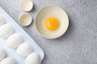 Bir sürü çiğ tavuk yumurtası ve bir tanesinin kasesi gri masada kırılmıştı.